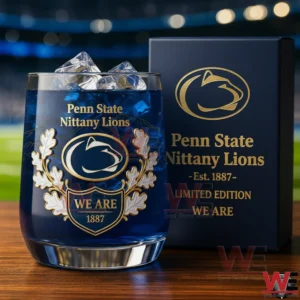 Penn State Nittany Lions We Are 1887 Whiskey Glass 3 A close view of a Penn State Nittany Lions whiskey glass with ice placed on a wooden surface next to a branded collector box!