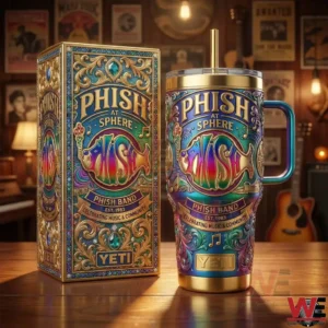 A YETI tumbler and presentation box with Phish at Sphere design placed on a wooden table surrounded by guitars and vintage music decor!