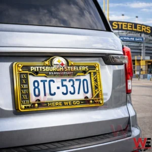 Rear view of a silver SUV with a Pittsburgh Steelers license plate frame showing the number 8TC5370 and Here We Go text near a Steelers stadium!