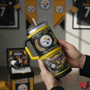 Hands holding a black and gold Pittsburgh Steelers 93rd anniversary insulated tumbler with yellow handle and straw in a Steelers themed room.