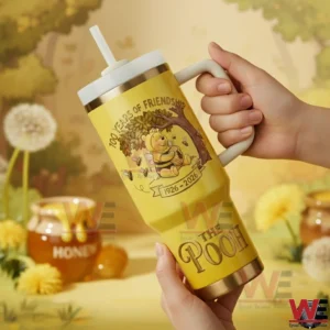Hands holding a yellow tumbler with bear and bee artwork in front of a warm natural background!