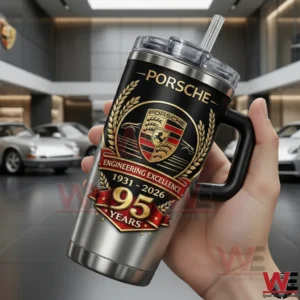Hand holding a Porsche insulated tumbler with anniversary design inside a luxury car showroom!