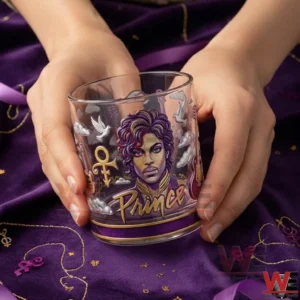 Hands holding a clear decorative glass with a purple illustrated portrait and the word Prince displayed on a purple fabric background!