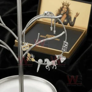 Adjustable charm bracelet on a metal stand with letter B bee microphone unicorn cozy text and crystal charms with Queen B gift box in the background.