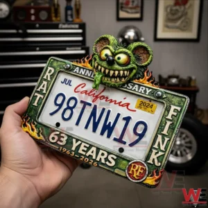 Rat Fink 63rd Anniversary Car License Plate Frame 3 Hand holding a Rat Fink anniversary license plate frame with a green monster head flames and sixty three years details in a garage background.