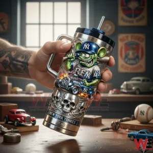 Hand holding a stainless travel tumbler with metal handle black lid and straw featuring a green cartoon character in a Yankees cap with bat hot rod car flames skull art and New York Yankees branding in a workshop scene.