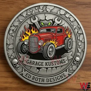Close up of a Garage Kustoms Ed Roth Designs metal coin featuring a red hot rod with flames wrenches and skull accents on a wooden surface!