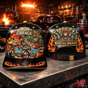Two black snapback caps on a metal table in a garage showing Iron Garage Rat Fink artwork and a Built Not Bought skull engine graphic.