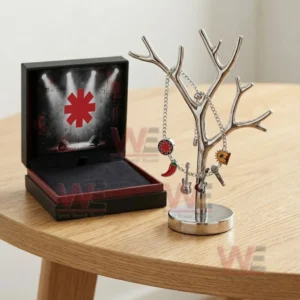 Silver adjustable charm bracelet with red asterisk chili pepper guitars microphone and sun palm charms hanging on a jewelry tree stand next to an open black concert themed gift box.