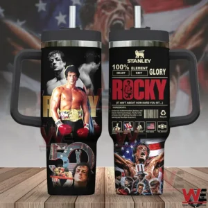 Two sided view of a black Rocky themed handled tumbler with straw featuring Rocky boxing artwork and bold Rocky text displayed on a wooden surface with a dramatic patriotic background!