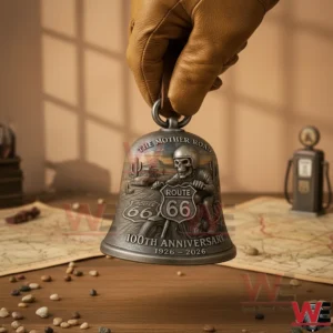 A hand holding a Route 66 anniversary bell with detailed metal relief artwork showing a biker desert road signs and classic travel elements!