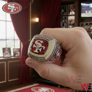 Hand holding a San Francisco championship ring with a red centerpiece and SF logo in a stylish room setting!