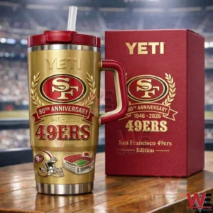 Gold and red San Francisco 49ers eightieth anniversary insulated tumbler with handle and straw lid next to a matching red limited edition gift box on a wooden surface with a blurred stadium behind!