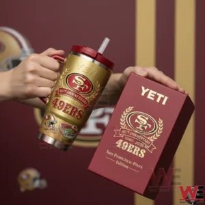 Two hands holding a gold San Francisco 49ers eightieth anniversary handled tumbler with red straw lid and a matching red limited edition gift box against a team themed background!