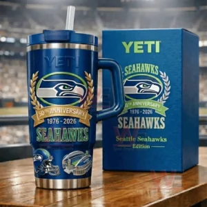 Navy YETI Seahawks 50th Anniversary tumbler next to a navy Seahawks themed gift box on a table with a blurred stadium behind!