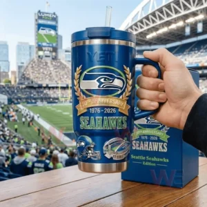 Hand holding a navy YETI Seahawks 50th Anniversary tumbler with a football stadium and field in the background!