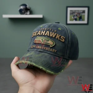 Hand holding a distressed baseball cap with embroidered team design inside a simple indoor setting!