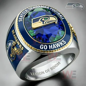 Close up of a Seattle Seahawks themed ring with blue green gemstone face hawk head logo Seattle Seahawks Football and Go Hawks text gold trim helmet side graphic and Legion of Boom engraving inside the band