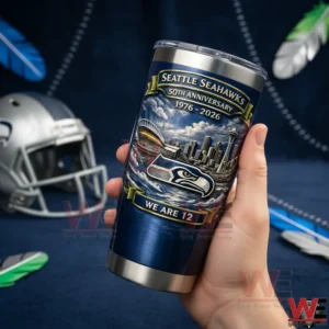 Seattle Seahawks WE ARE 12 50th Anniversary 1976-2026 Tumbler Cup 3 Person holding a navy blue Seattle Seahawks 50th anniversary tumbler with Seahawks logo and We Are 12 text in front of a football themed background with a helmet!