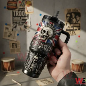 Sex Pistols Never Mind the Bollocks, Here's the 40oz Tumbler With Handle 5 Hand holding a black insulated tumbler with handle and straw featuring punk skull artwork in a creative room!