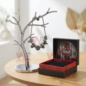 Adjustable dark silver tone charm bracelet on a jewelry tree stand with skull geometric star and band themed charms beside an open black and red Slipknot gift box.