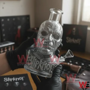 Slipknot Band Shaped Bong 4 Black gloved hands holding a clear glass masked face water pipe with Slipknot logo and side bowl piece in a music themed room!