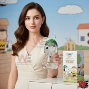 Clear glass Snoopy anniversary figure held in front of a Peanuts themed background with display box!