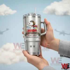 Hands holding a silver handled tumbler with straw featuring a pilot dog with aviator goggles and red scarf plus seventy fifth anniversary years one nine five zero to two zero two five flying ace edition on a sky background with clouds!