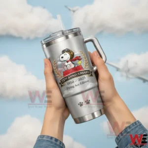 Hands raising a silver handled tumbler with straw featuring a pilot dog aviator goggles red scarf laurel wreath and seventy fifth anniversary years one nine five zero to two zero two five flying ace edition against a sky with clouds and airplanes!