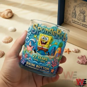 A close view of a hand holding a SpongeBob anniversary whisky glass with detailed ocean themed artwork and a joyful twenty seven year celebration look!