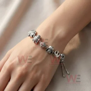 Adjustable charm bracelet on a wrist with Star Wars inspired spaceship droid alien head helmet and symbol charms in silver tones.