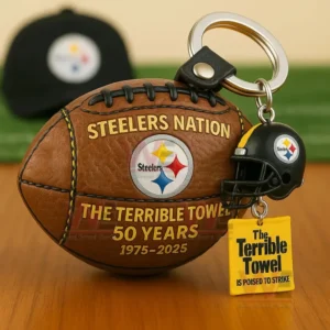 Brown football keychain with Steelers Nation design and Terrible Towel anniversary charms on a wooden table with a blurred sports background.