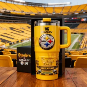 Yellow Stanley Steelers tumbler with handle Steelers logo Terrible Towel design and Here We Go text shown with Steelers x Stanley boxes in a football stadium setting