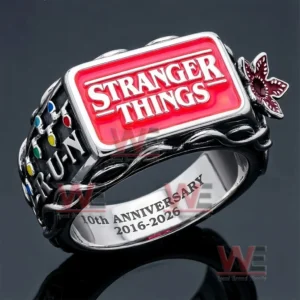 Stranger Things tenth anniversary ring with red logo face silver and black band vine details side butterfly emblem multicolored dots R U N text and engraved two thousand sixteen to two thousand twenty six shown with string lights background!