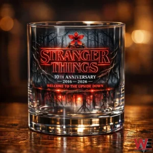 Clear drinking glass with a glowing red forest illustration displayed on a wooden table in low warm lighting!