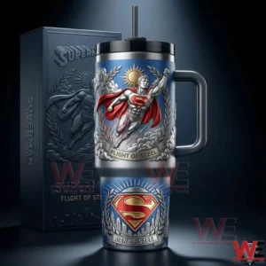 A blue handled insulated tumbler showcasing a flying heroic figure with a red emblem and metallic engraved details presented in a dramatic studio setting!