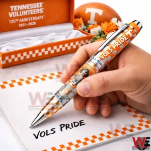Hand holding an orange and white checkered Tennessee Volunteers pen writing Vols Pride on a notebook with an orange anniversary box behind it!
