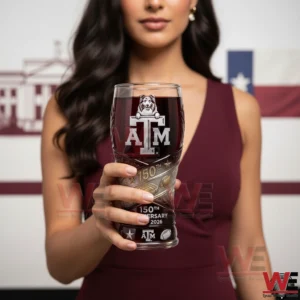 A person holding a Texas AM anniversary beer glass with detailed emblem and celebratory artwork!