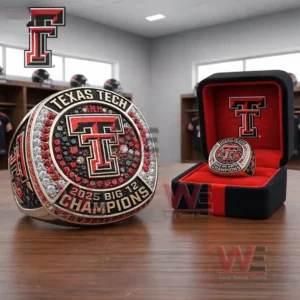 Texas Tech 2025 Big 12 Champions ring with a double T emblem and red black and clear stones displayed next to a black and red presentation box in a locker room setting!