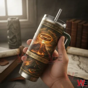 The Lord Of The Rings 25Th Anniversary One Ring 2001-2026 Yeti Tumbler 4 Hand holding a Lord of the Rings twenty fifth anniversary tumbler with green handle and fiery ring volcano artwork in front of books and a map!