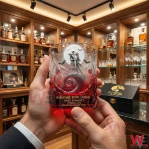 The Nightmare Before Christmas Dark Romance Collector Whiskey Glass 6 A Dark Romance themed collector whiskey glass held in hands with intricate gothic artwork and a refined whiskey cabinet behind!