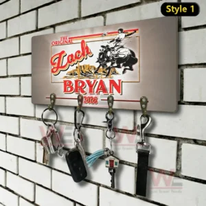 Wall mounted key holder on a white brick wall with a vintage western Zach Bryan 2026 design and four metal hooks holding keys a car fob a tassel keychain a house key and a lanyard!