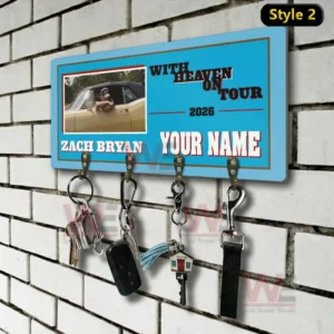 Blue ticket style wall key holder on a white brick wall featuring with heaven on tour 2026 Zach Bryan and a custom name area with four metal hooks holding keys a car fob a tassel keychain a house key and a lanyard!
