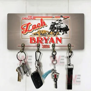 Wall key holder on a white background with a vintage western Zach Bryan 2026 design and four metal hooks holding keys a car fob a tassel keychain a house key and a lanyard!