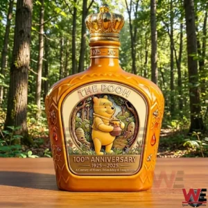 Golden The Pooh 100th anniversary bottle with crown cap and honey themed artwork standing on a wooden table in a forest background!