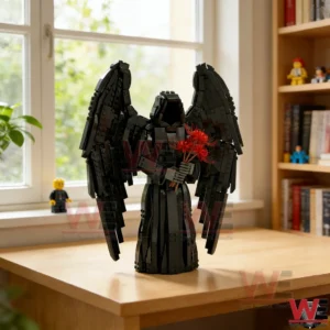 A black gothic angel brick sculpture with wings and red flowers is displayed on a table by a window!