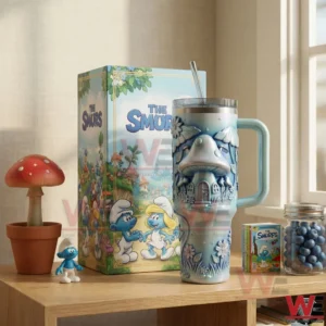Smurfs themed tumbler with mushroom house artwork handle clear lid and straw displayed beside a matching collector box on a wooden shelf!