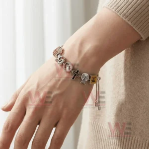 The Weeknd After hours, Dawn FM XO Until We Overdose Adjustable Charm Bracelet 4 Hand wearing a silver adjustable charm bracelet with XO globe cross and radio signal charms with sliding chain ends.