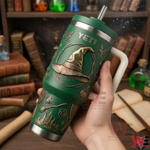Hand holding a green Yeti tumbler with a witch hat emblem and raised magical icons near books and bottles!