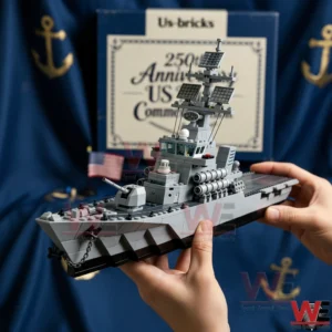 A brick built naval warship model held in hands with a US Navy anniversary backdrop behind!